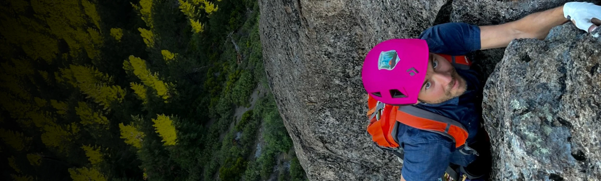 A climber moving across sunlit rock outdoors.
